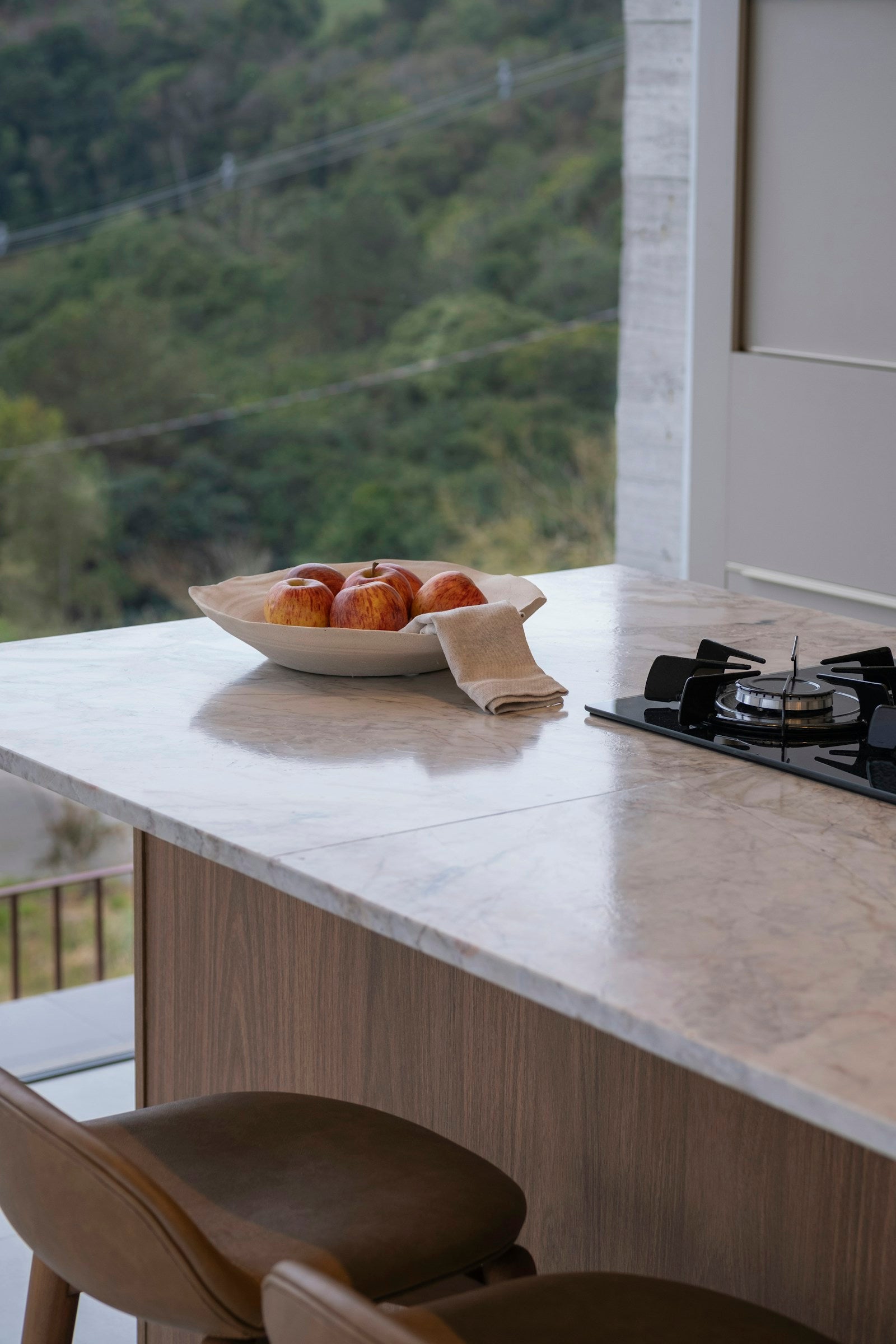 Bowl of fruit on a marble kitchen island beside a window